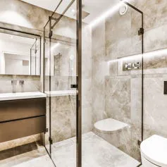 Marble bathroom with light brown tones and glass shower box