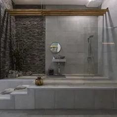 Marble bathroom elevated from the floor with black split wall and grey marble tiles