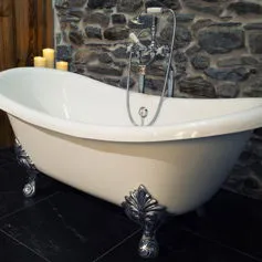 Bagno con marmi neri e sassi <br>tranciati sul muro