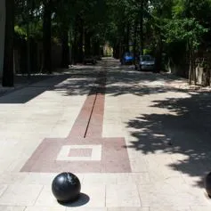 Viale con marmo bocciardato e sfere di metallo nero come paracarri